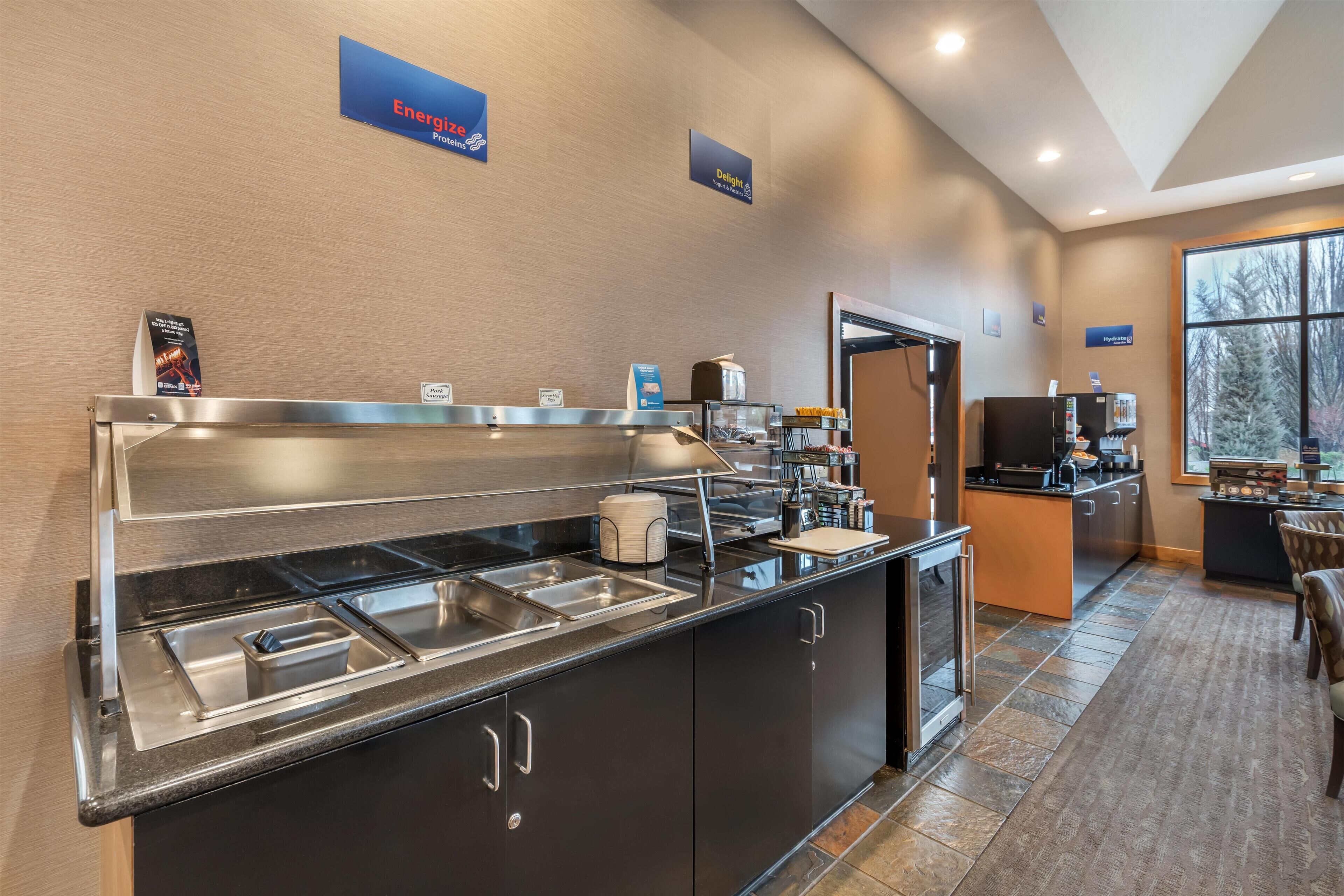 A modern hotel kitchen with a buffet area, including stainless steel sinks and a coffee station.