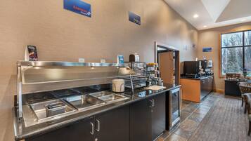 A modern hotel kitchen with a buffet area, including stainless steel sinks and a coffee station.