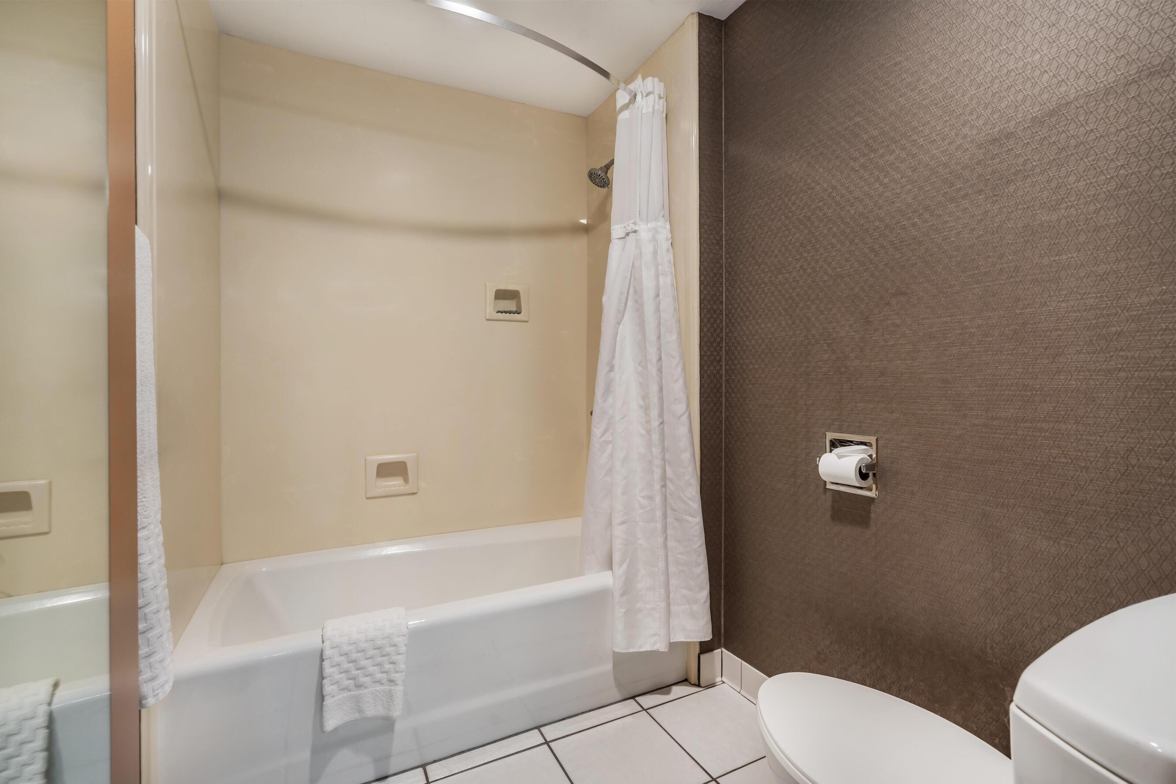 Een badkamer met een bad, toilet en douchegordijn.
