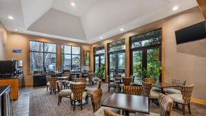 A restaurant with high ceilings, large windows, and a mix of seating arrangements including tables and booths. - Best Western Windsor Inn (Ashland)