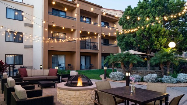 An outdoor patio area with a fire pit, seating, and string lights.