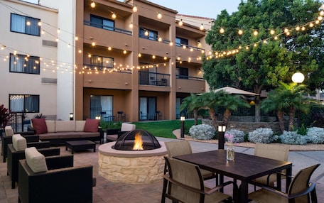 An outdoor patio area with a fire pit, seating, and string lights.