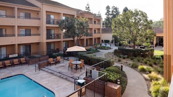 Une cour d’hôtel avec une piscine, des espaces de détente en plein air et un jardin aménagé.