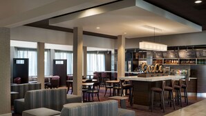 A modern hotel lobby with seating areas, a bar, and a menu display.