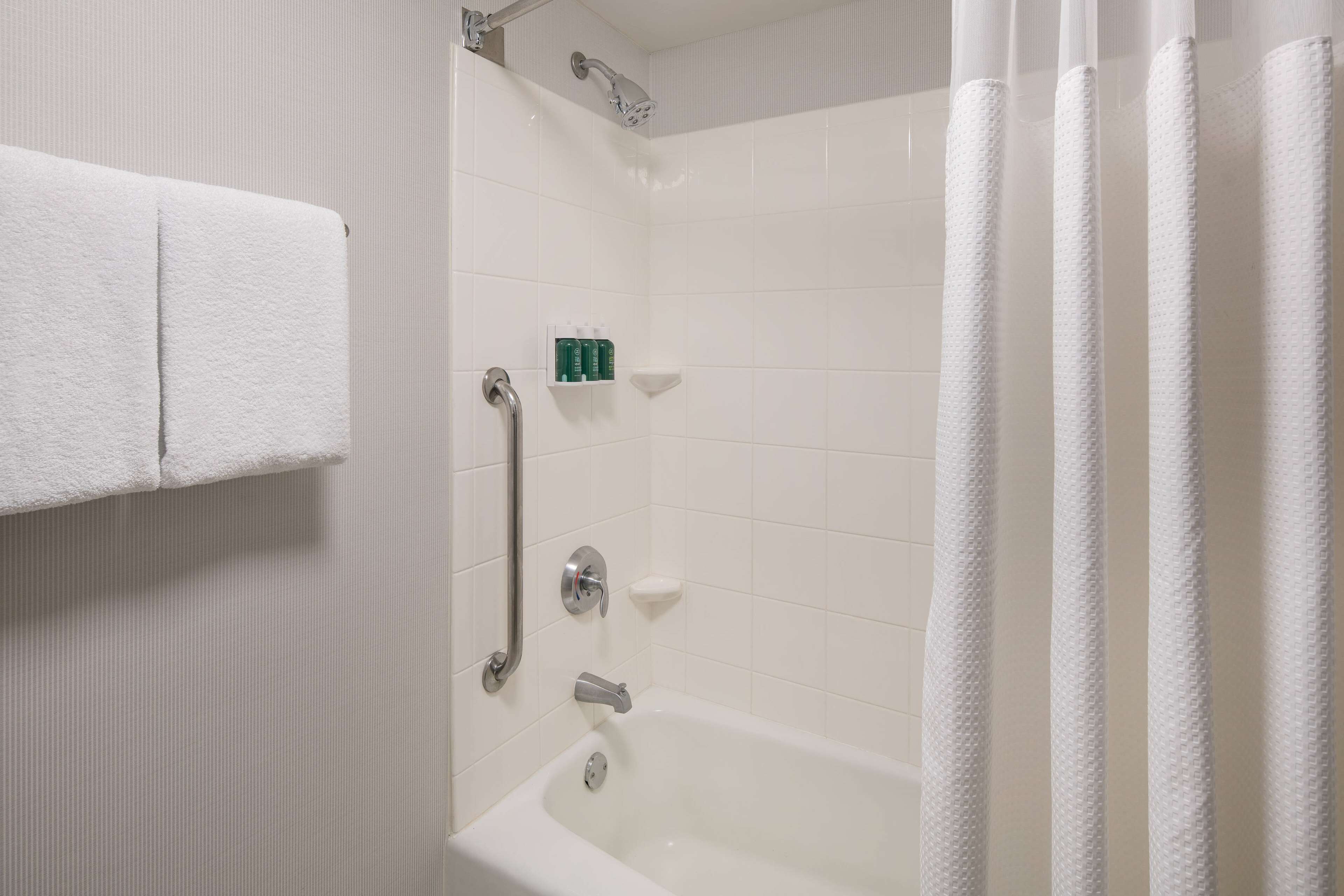 Une salle de bain blanche avec une baignoire, une douche et un porte-serviettes.