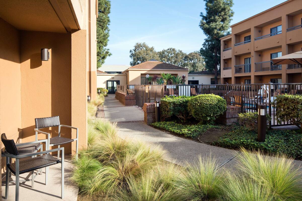 A courtyard with outdoor seating, a pathway, and a building with multiple balconies.