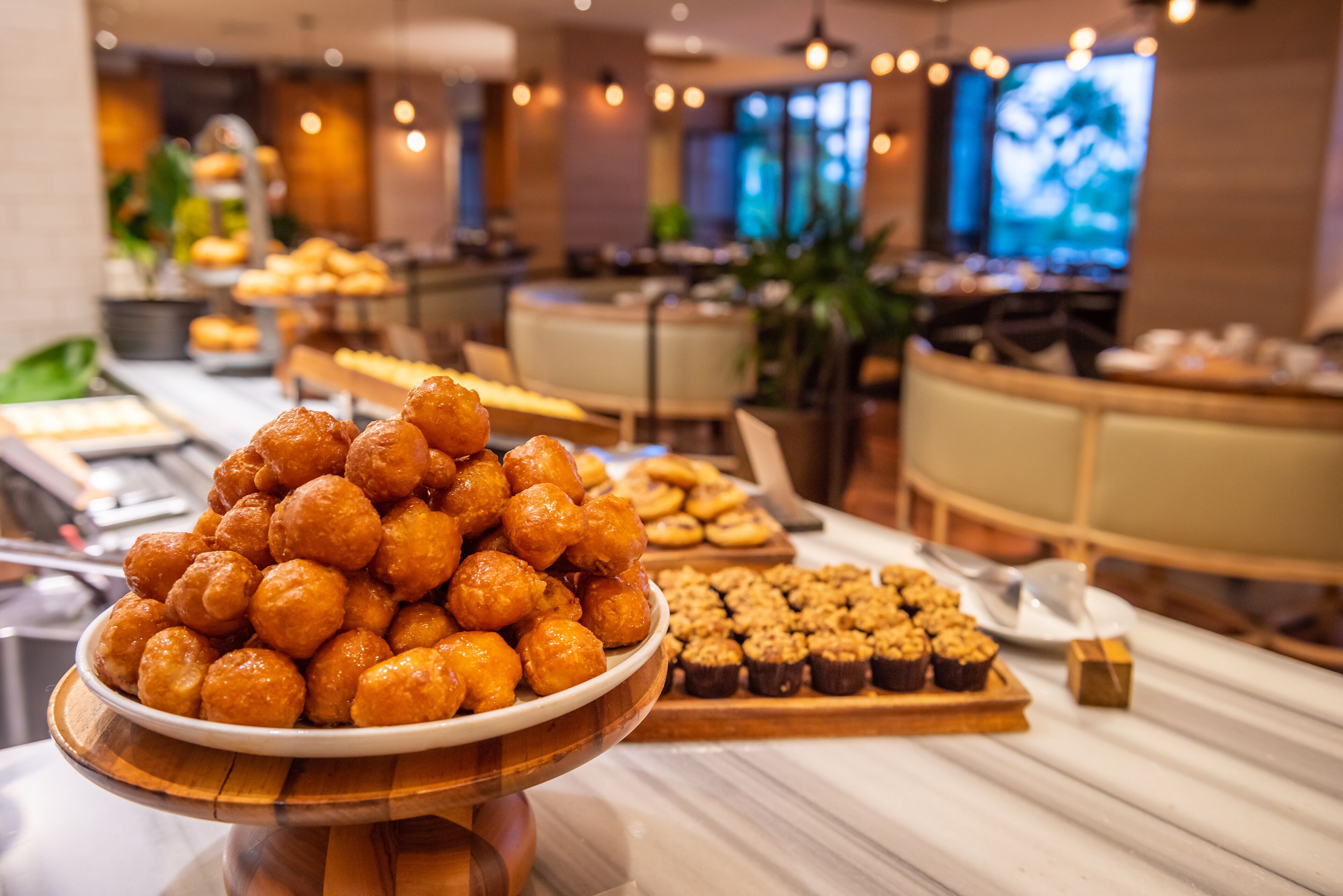 Un buffet proposant une variété de viennoiseries et de desserts, avec, au premier plan, un grand saladier rempli de petits gâteaux ronds.