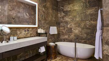 A modern bathroom with a freestanding bathtub, a large mirror, and a vanity with a marble countertop.