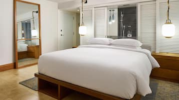 A hotel room with a large bed, a mirror, and a window with blinds.