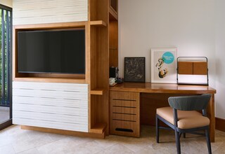 A modern room with a built-in TV, a desk, a chair, and a framed artwork on the wall.