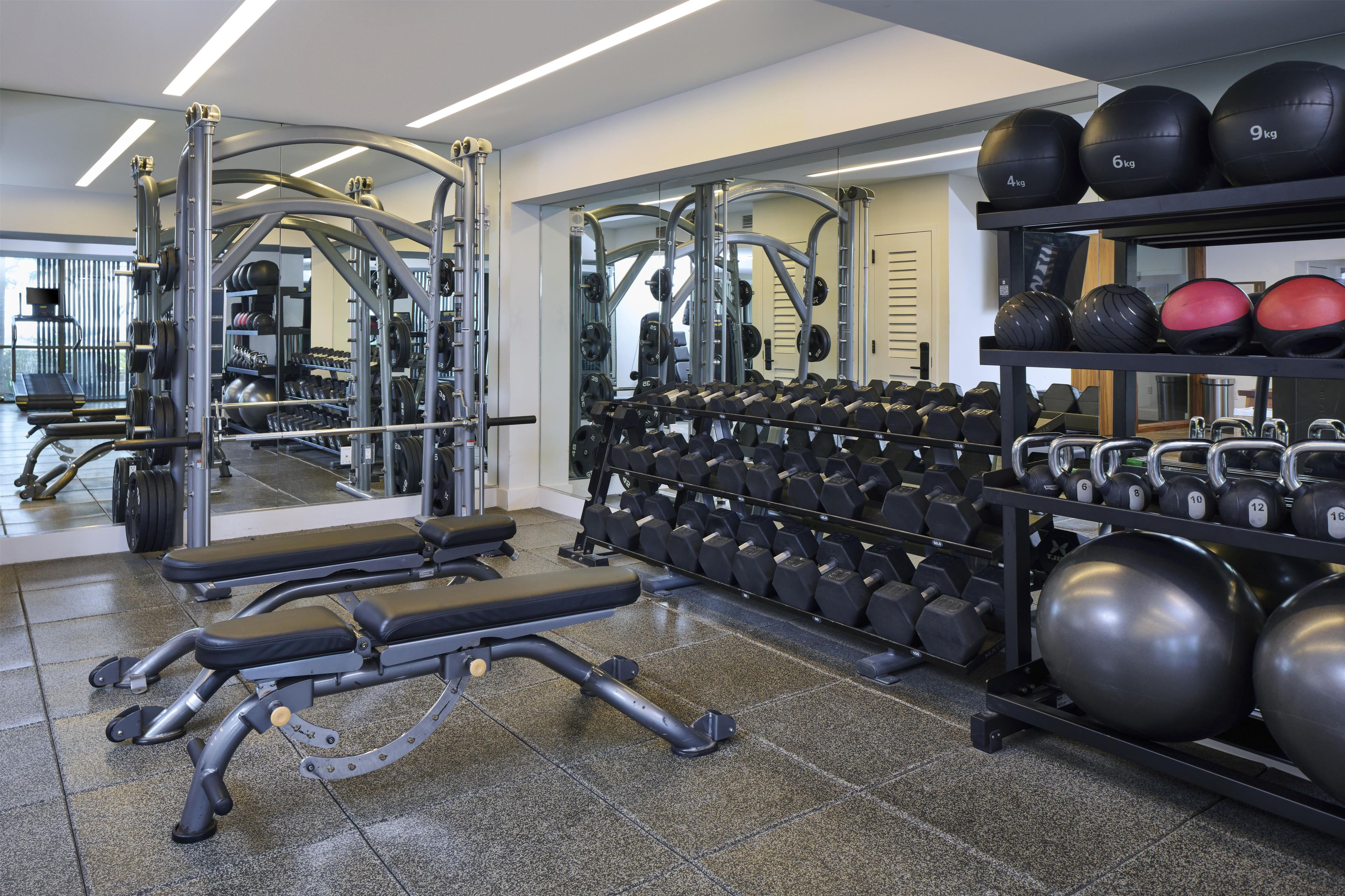 Une salle de sport équipée de matériel de musculation, de tapis de course et de ballons d’exercice.