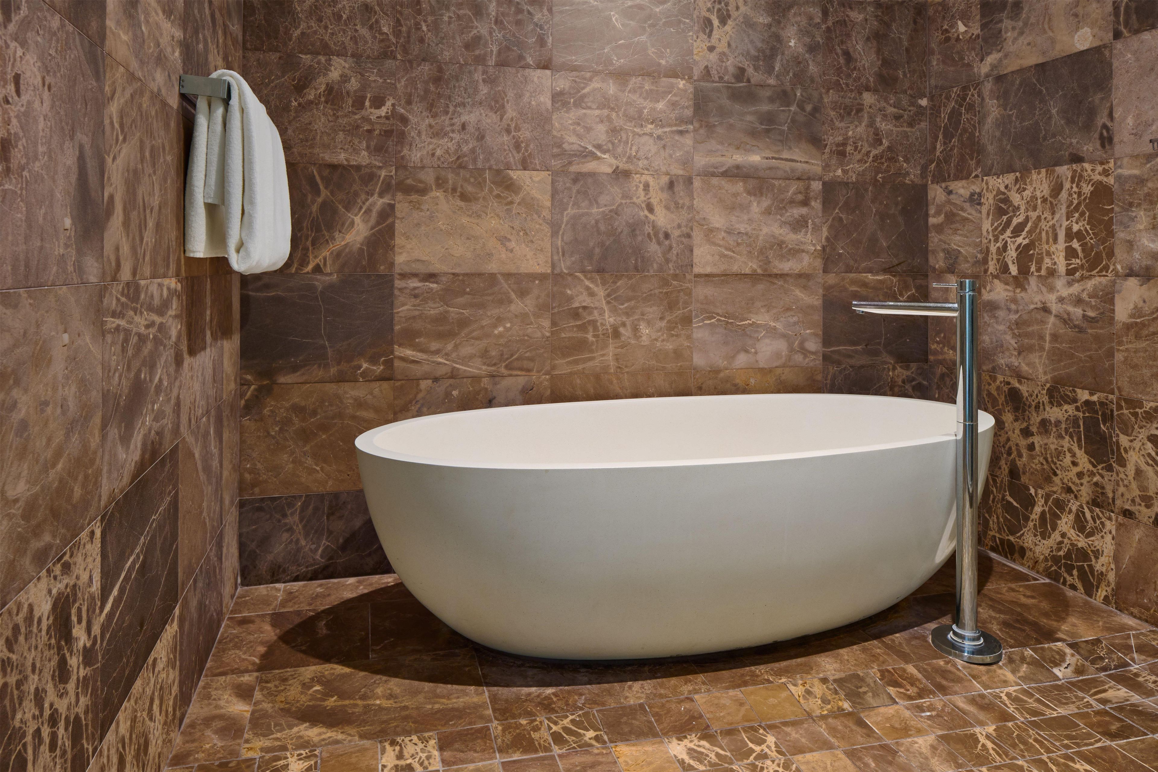 Un baño moderno con una bañera independiente, un perchero y un grifo de cromo.