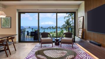 A modern living room with a large sliding glass door leading to a balcony with a view of the ocean.