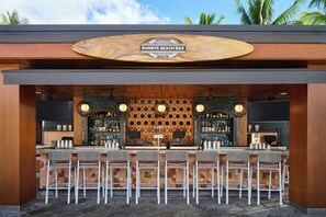 A bar with a wooden sign, multiple bar stools, and a patterned wall. - Andaz Maui at Wailea Resort - a concept by Hyatt (Kihei)