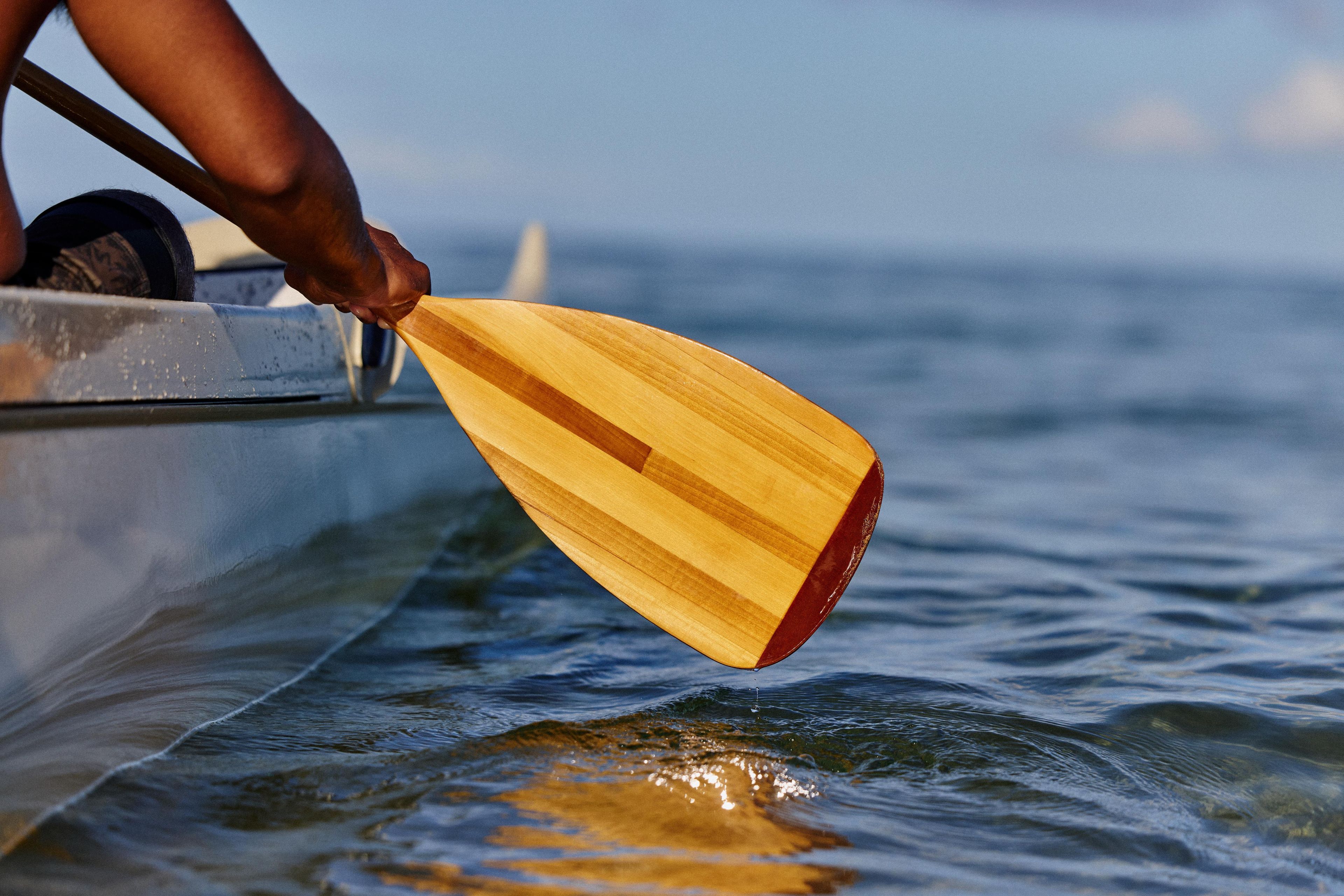 A wooden paddle in a boat, with water and a distant horizon.