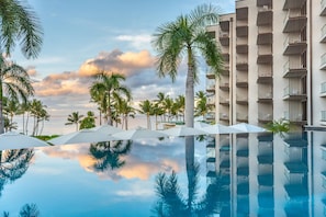 Una piscina que refleja palmeras y un edificio con balcones.