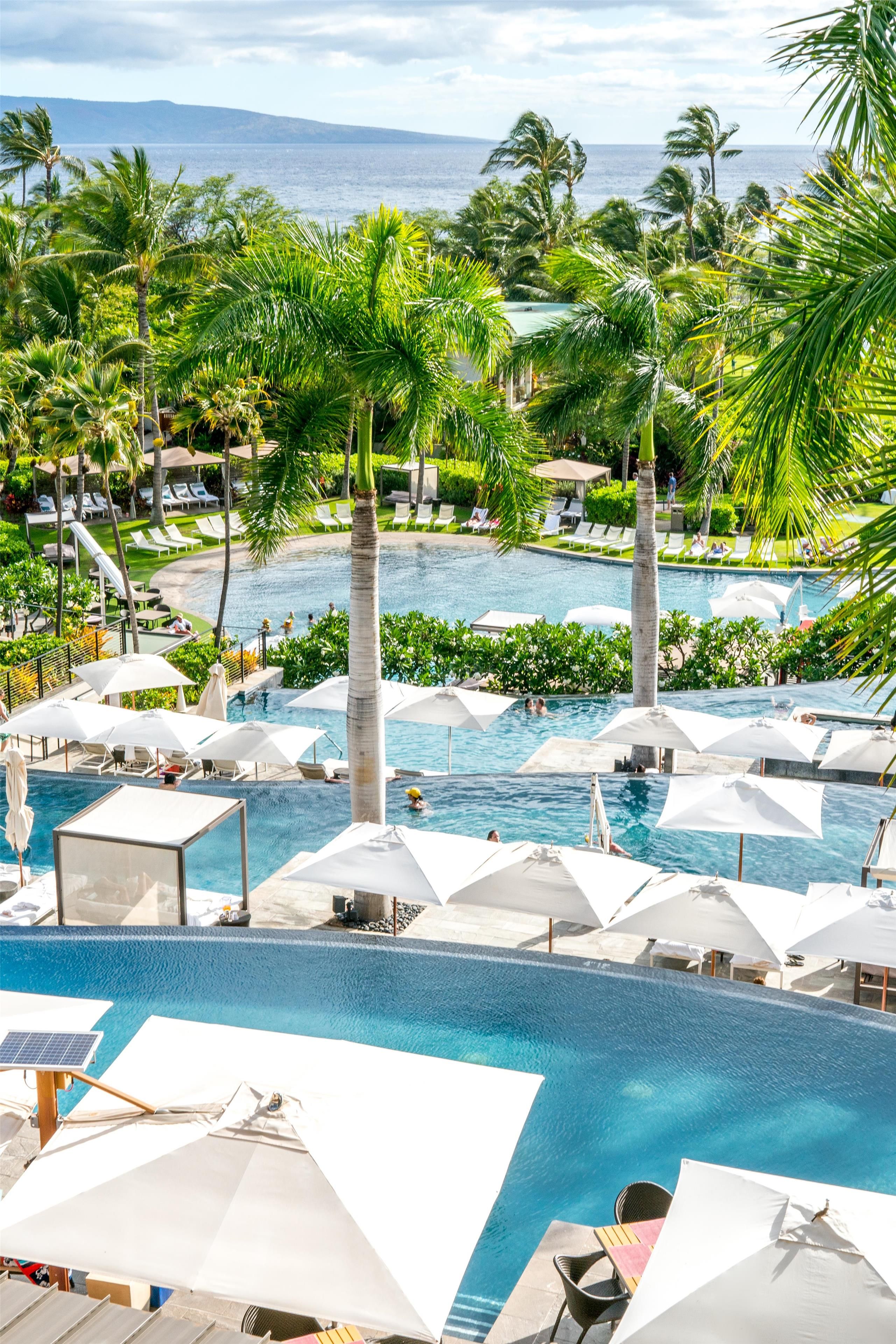A resort with multiple swimming pools, palm trees, and lounge chairs.