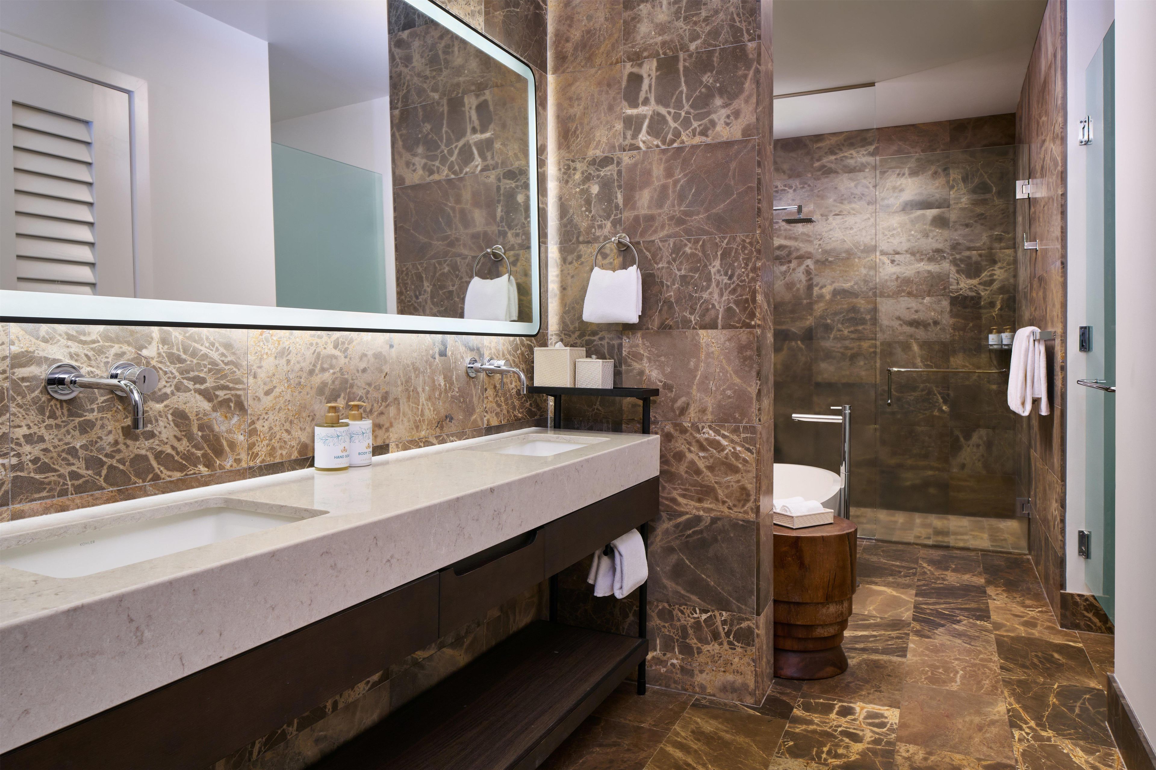 A modern bathroom with a dual sink vanity, a large mirror, and a shower area.