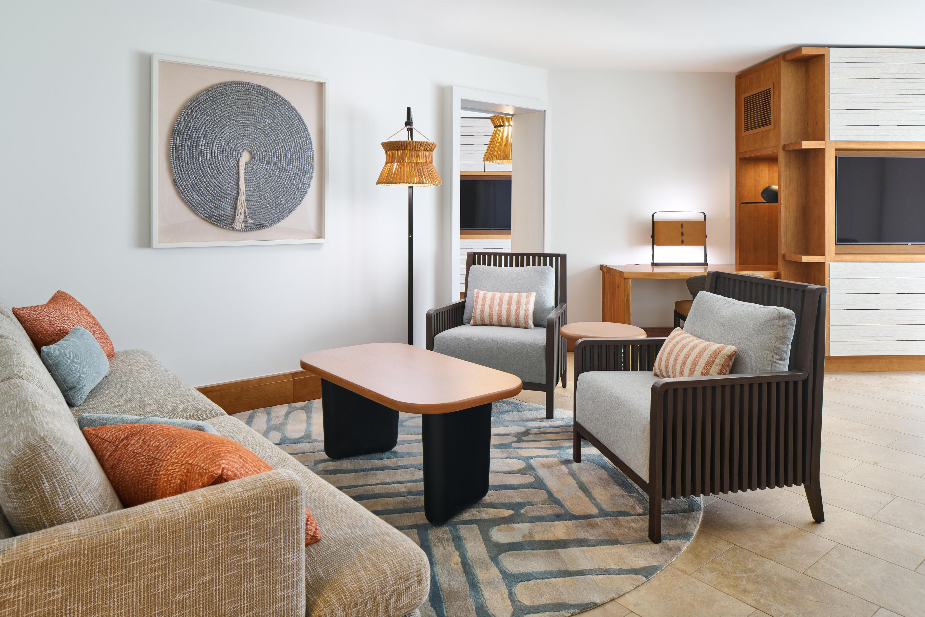 A modern living room with a sofa, armchairs, a coffee table, and a TV.