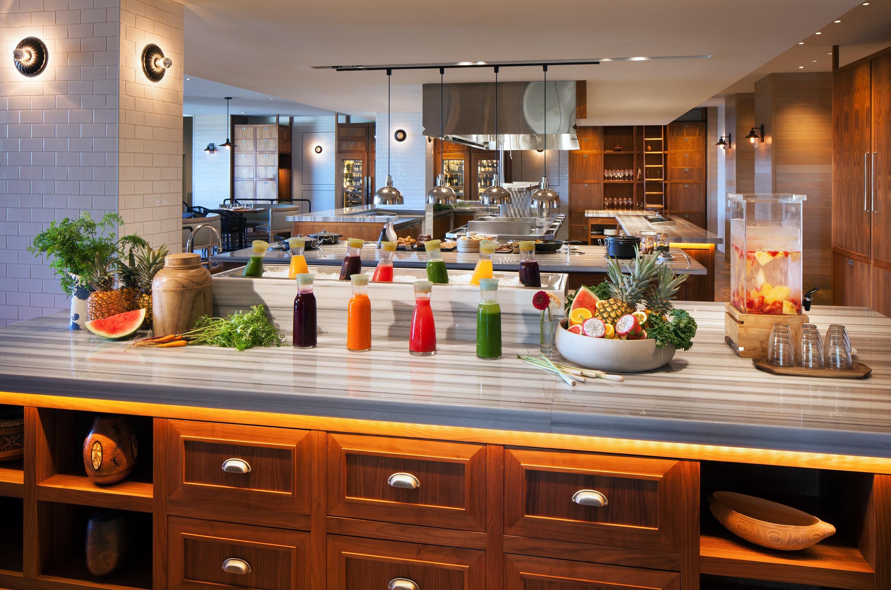 A modern kitchen with a marble countertop, various food items, and a fruit bowl.