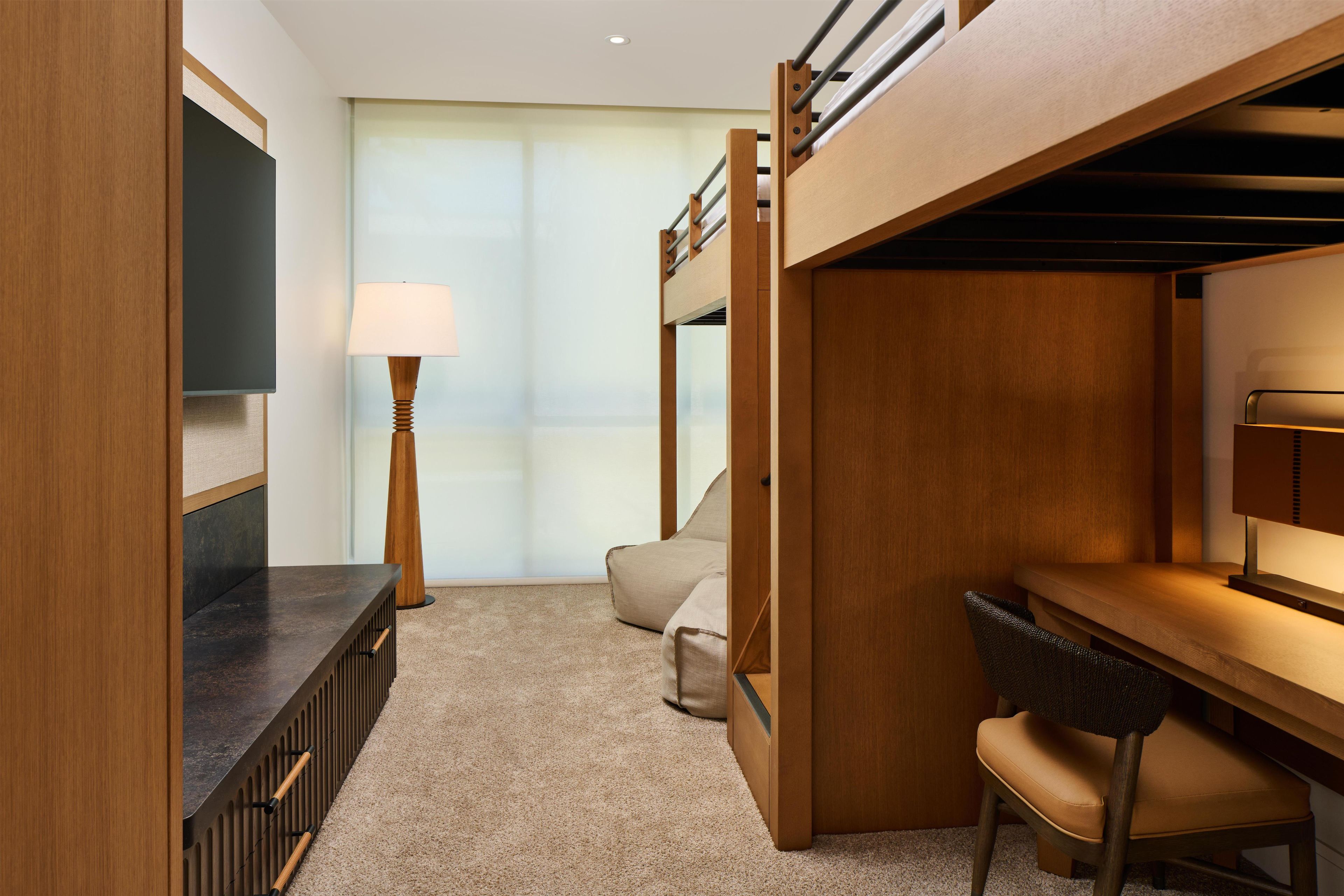 Habitación con literas, escritorio, silla, lámpara y ventana con cortinas.