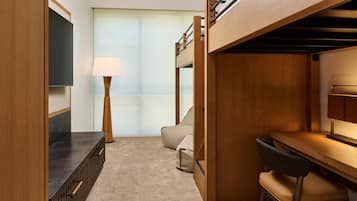 Habitación con literas, escritorio, silla, lámpara y ventana con cortinas.