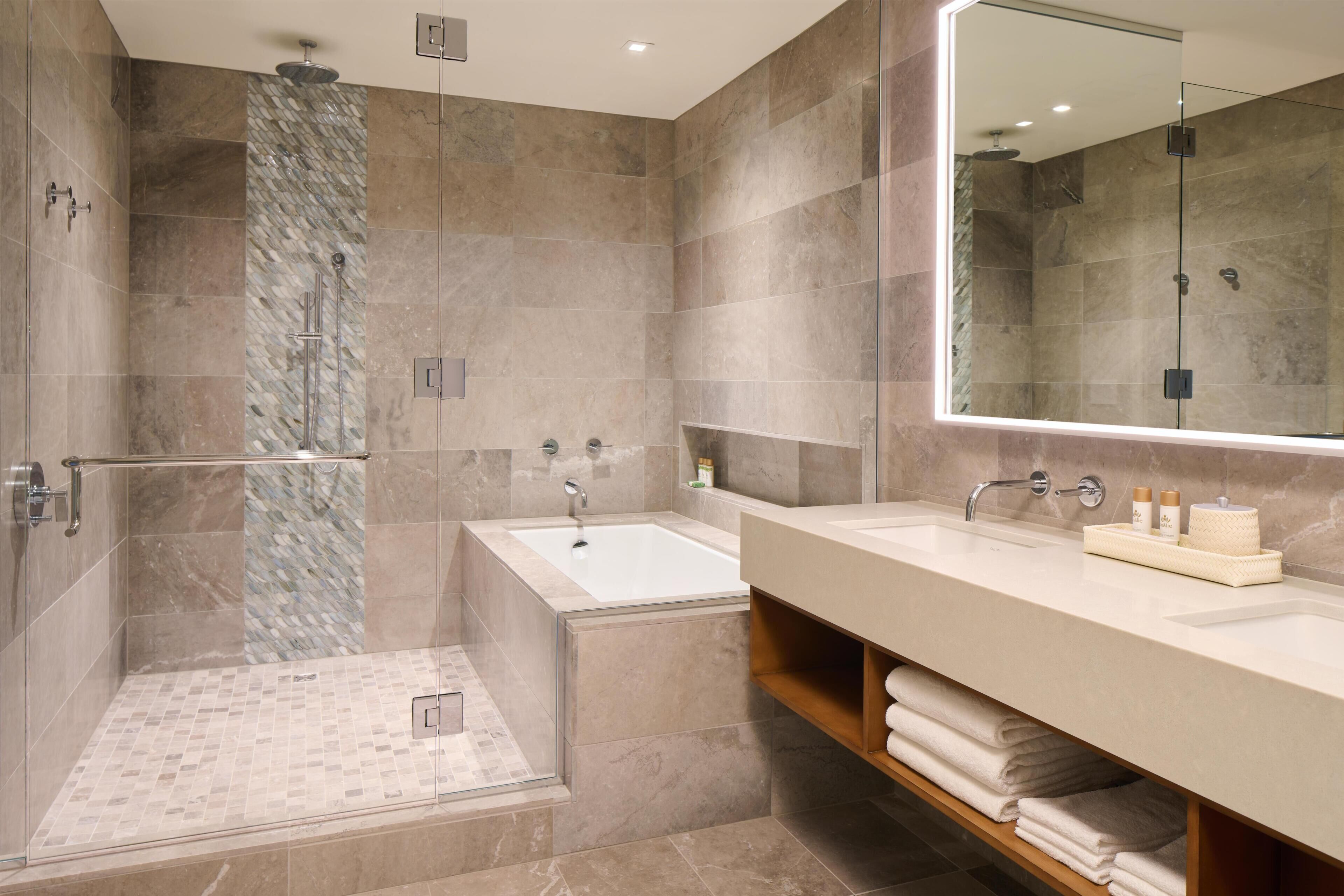 A modern bathroom with a glass-enclosed shower, a standalone bathtub, and a large mirror above a vanity with a towel rack.