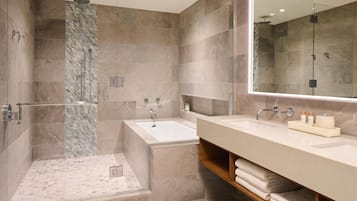 A modern bathroom with a glass-enclosed shower, a standalone bathtub, and a large mirror above a vanity with a towel rack.