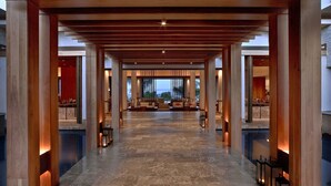 A spacious lobby with a high ceiling, wooden columns, and a marble floor.