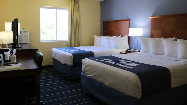 A hotel room with two beds, a desk, and a window with curtains. - Days Inn & Suites by Wyndham Gunnison (Gunnison)