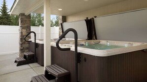 A hot tub with steps and a bench, surrounded by stone pillars and a covered patio area. - Days Inn & Suites by Wyndham Gunnison (Gunnison)