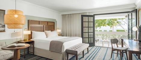 Une chambre d’hôtel comprenant un lit, des tables de chevet, un banc, une table à manger et un balcon avec vue.