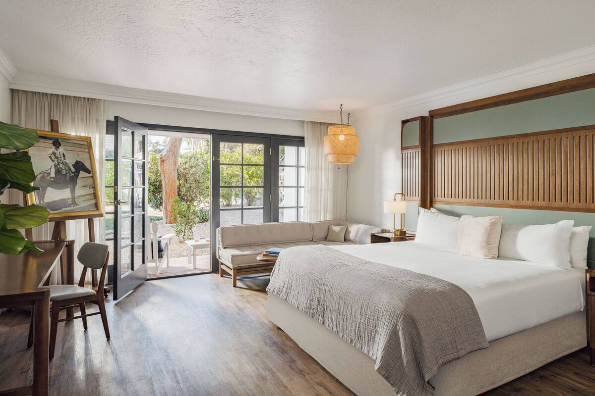 A hotel room with a bed, a sofa, a desk, and a chair.