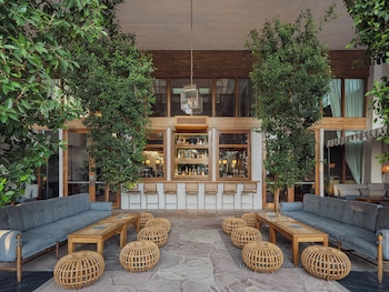 A spacious indoor area with a large seating area, a hanging woven light fixture, and a large tree. at The Scott Resort & Spa