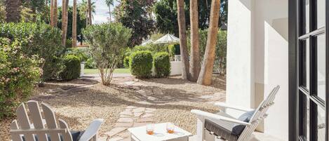 An outdoor patio with two Adirondack chairs, a small table, and a white umbrella.