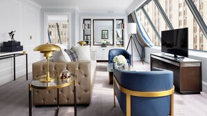 A modern living room with a sofa, armchair, and coffee table, a television, and a bookshelf. - The Langham, Boston (Boston)
