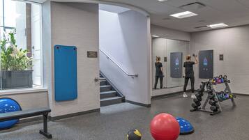 A gym with exercise equipment, a blue mat, and a red exercise ball.