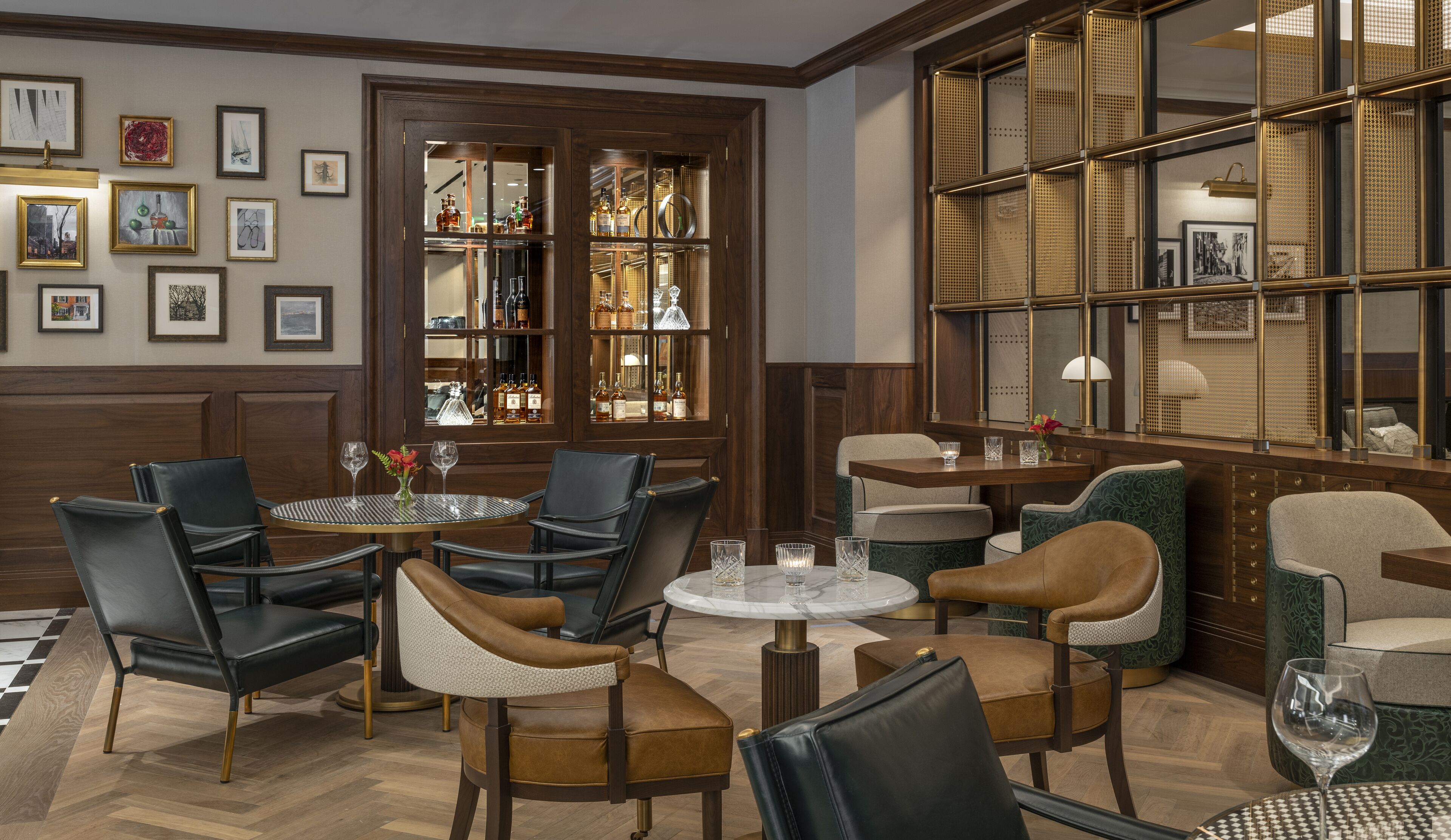 A well-lit, elegantly furnished lounge area with multiple seating options, including leather chairs and cushioned sofas, arranged around a central coffee table.