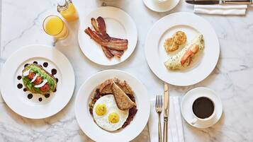Un desayuno con varios platos, incluyendo huevos, tocino, tostadas y un muffin.