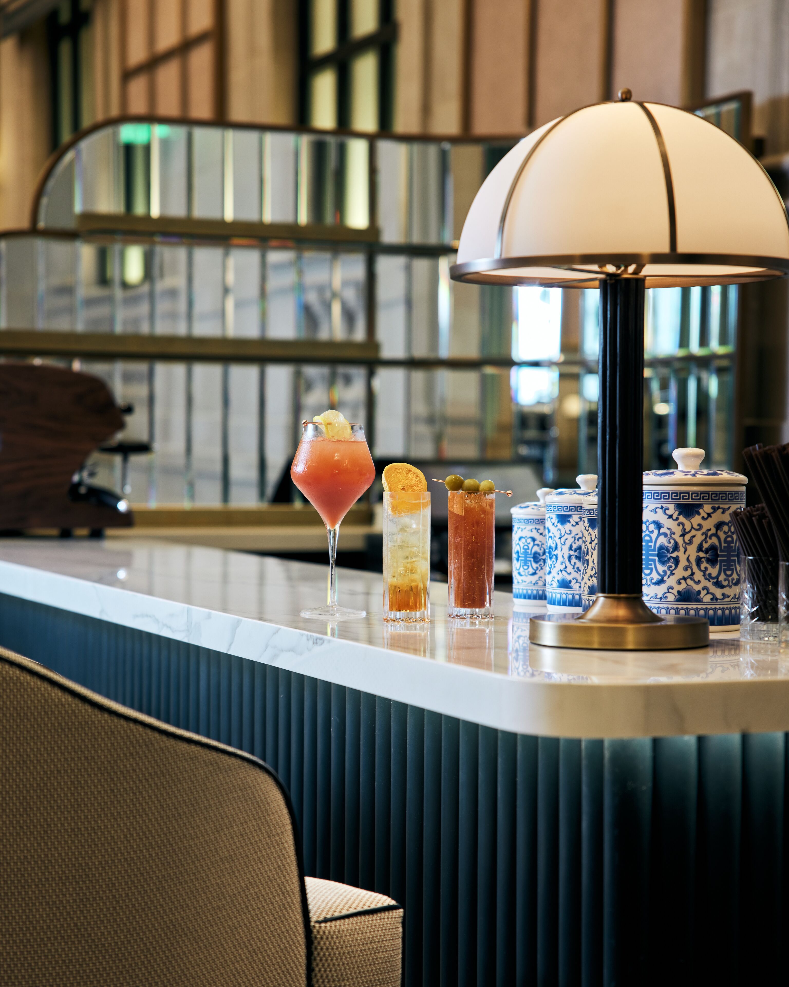 Un coin bar avec un comptoir en marbre, une lampe blanche et trois boissons.