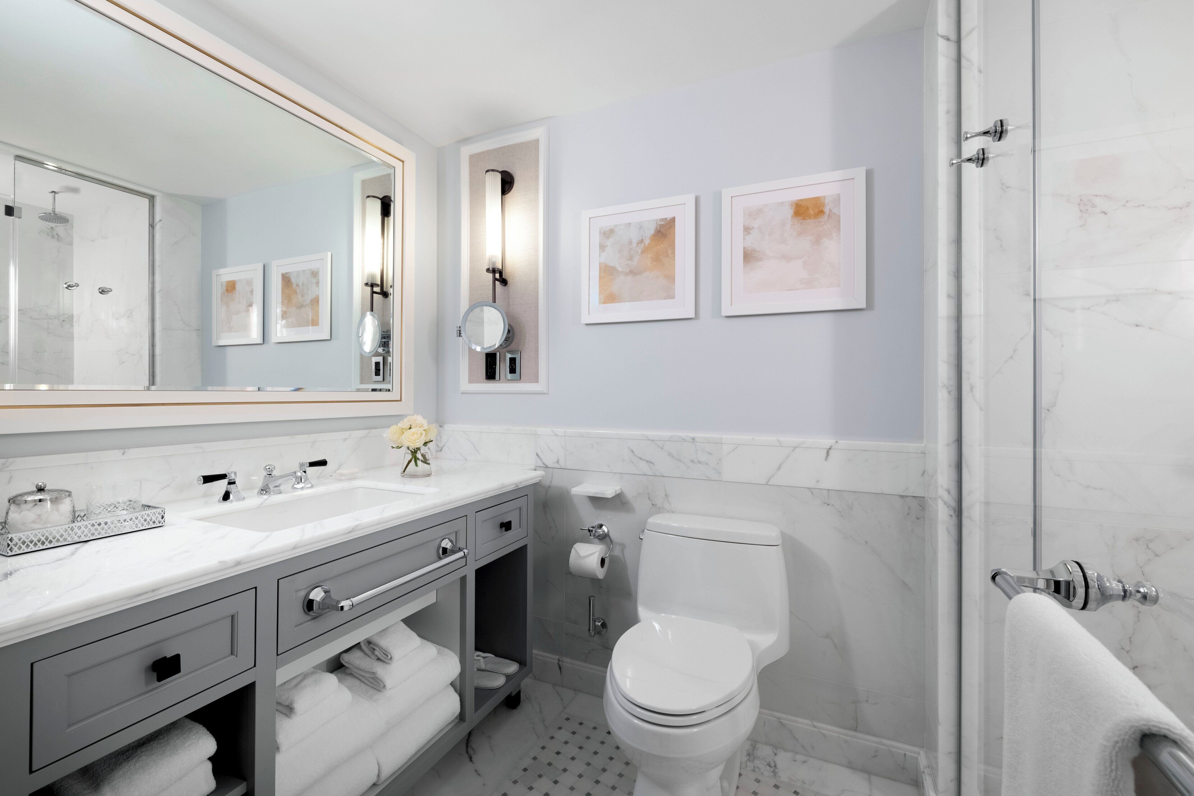 A modern bathroom with a large mirror, a toilet, a sink, and a shower.