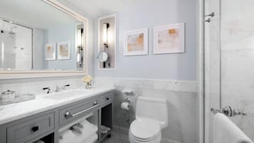 A modern bathroom with a large mirror, a toilet, a sink, and a shower.