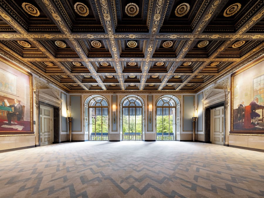 A grand hall with ornate ceiling and large windows.