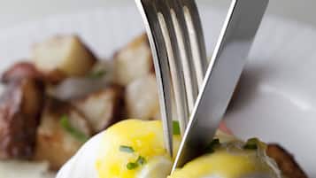 A breakfast dish with poached eggs, hollandaise sauce, and bacon on a white plate.