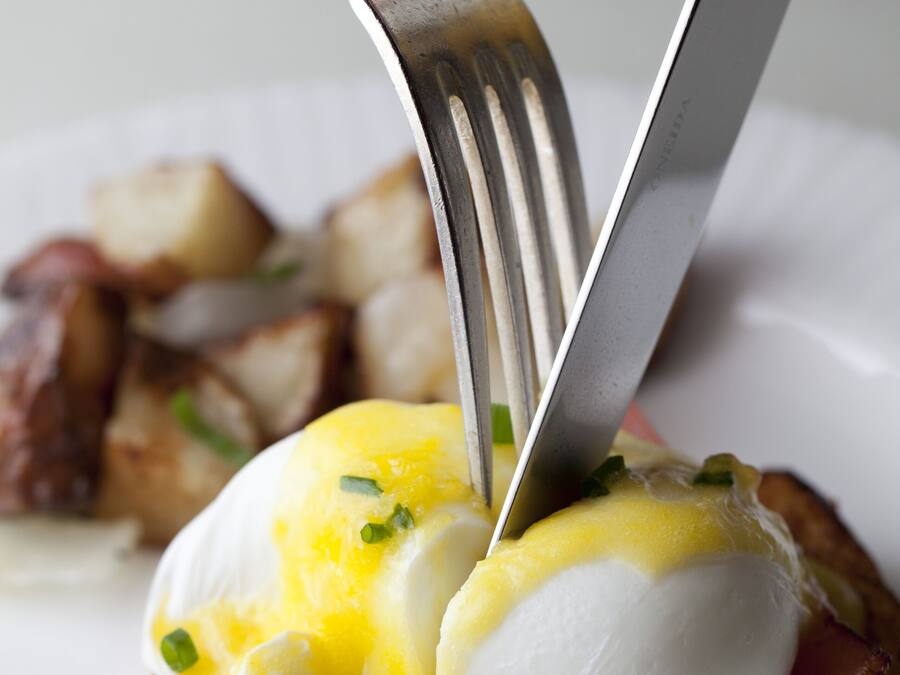 Ein Frühstücksteller mit pochierten Eiern, Sauce Hollandaise und Speck.