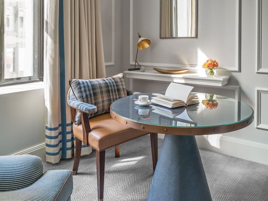 Ein gemütliches Zimmer mit einer Couch, einem runden Glastisch und Blick auf Gebäude.