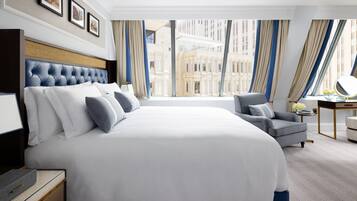 Camera d'albergo con un letto grande, una scrivania, una sedia e vista sulla città.