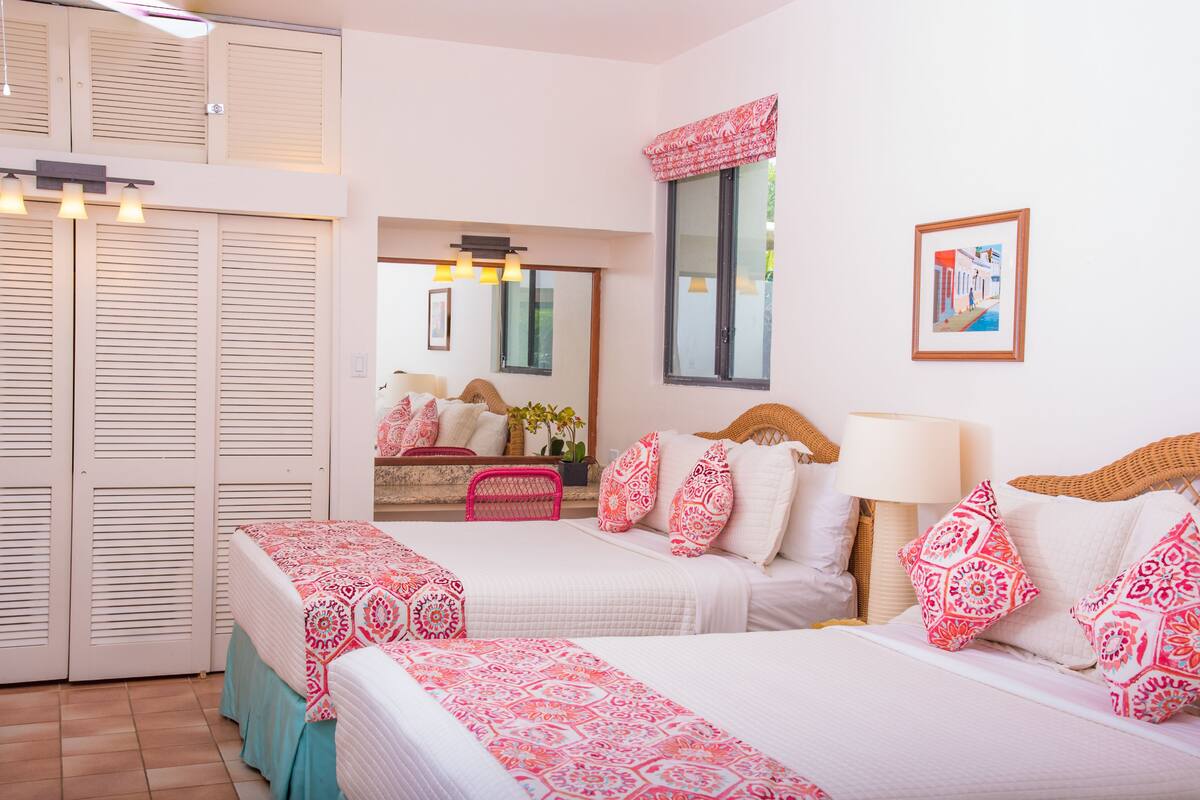 A bedroom with two beds, a large window, and a view of the outside.