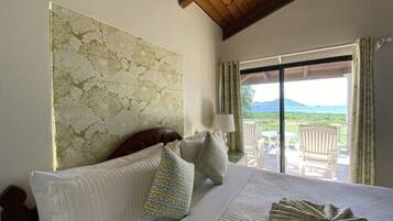 A hotel room with a large bed, a view of the outdoors, and a wooden ceiling.