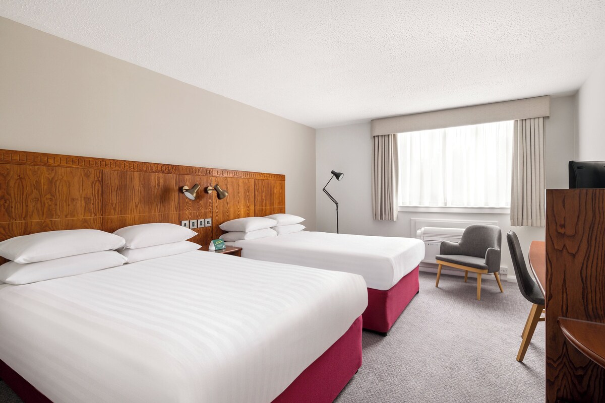 Una habitación de hotel con dos camas, un escritorio, una silla y un televisor.